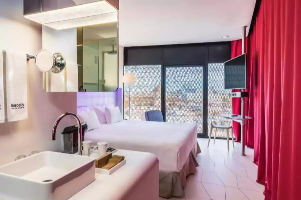 Habitación de hotel moderna con cama doble, cortinas rojas, lavabo y vista a la ciudad a través de grandes ventanales. Habitación de hotel moderna con cama doble, cortinas rojas, lavabo y vista a la ciudad a través de grandes ventanales.