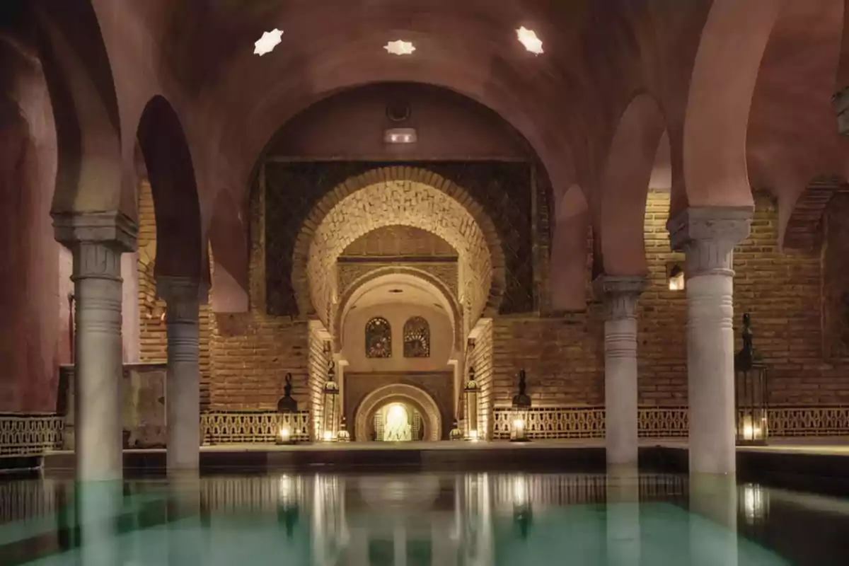 Un baño árabe con arcos de ladrillo, columnas de piedra y una piscina central iluminada por luces suaves. Un baño árabe con arcos de ladrillo, columnas de piedra y una piscina central iluminada por luces suaves.