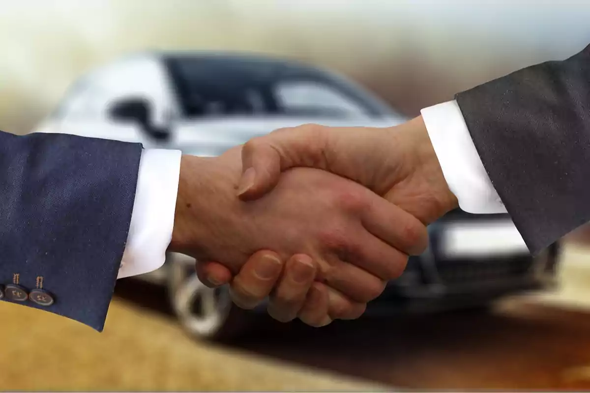Dos personas dándose la mano con un coche desenfocado al fondo