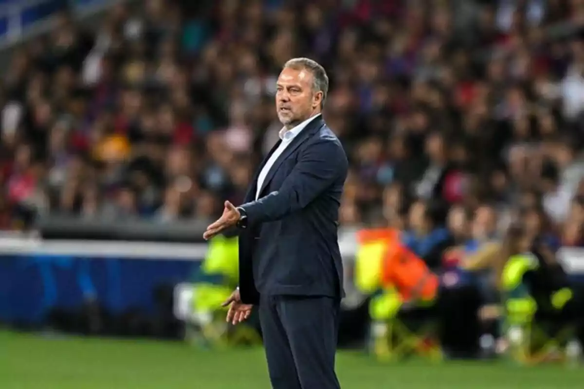 Un hombre de traje gesticula en un estadio lleno de espectadores.