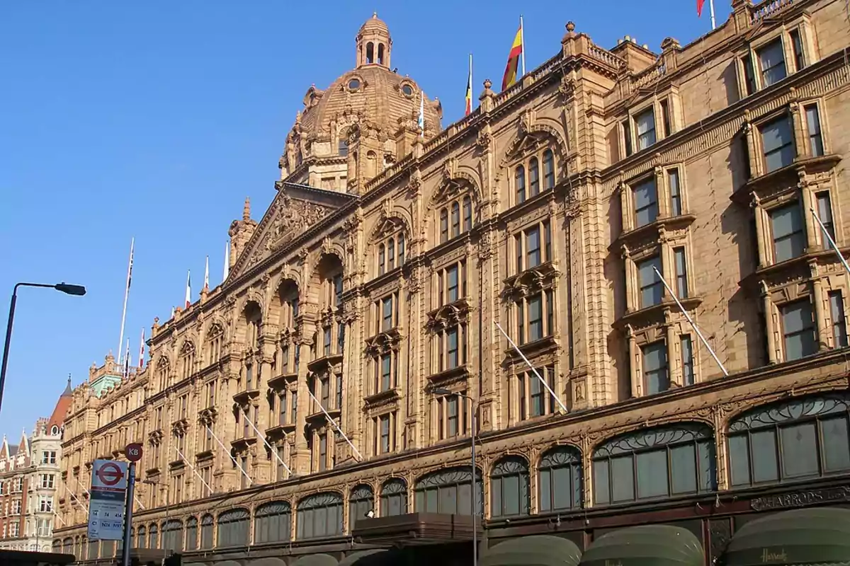 Fachada del edificio de Harrods en Londres con cielo despejado y varias banderas en la parte superior Fachada del edificio de Harrods en Londres con cielo despejado y varias banderas en la parte superior