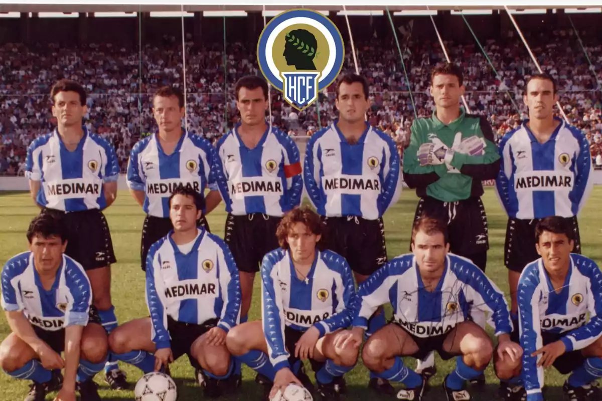 Un equipo de fútbol posando en el campo con uniformes a rayas azules y blancas y un logotipo en la parte superior.