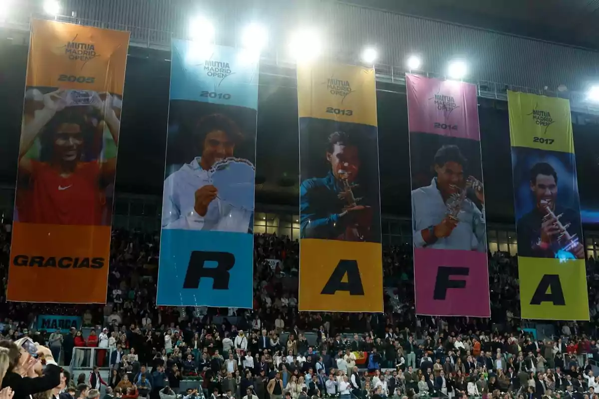 Banderas colgadas en un estadio con imágenes de un tenista y los años 2005, 2010, 2013, 2014 y 2017, formando la palabra 