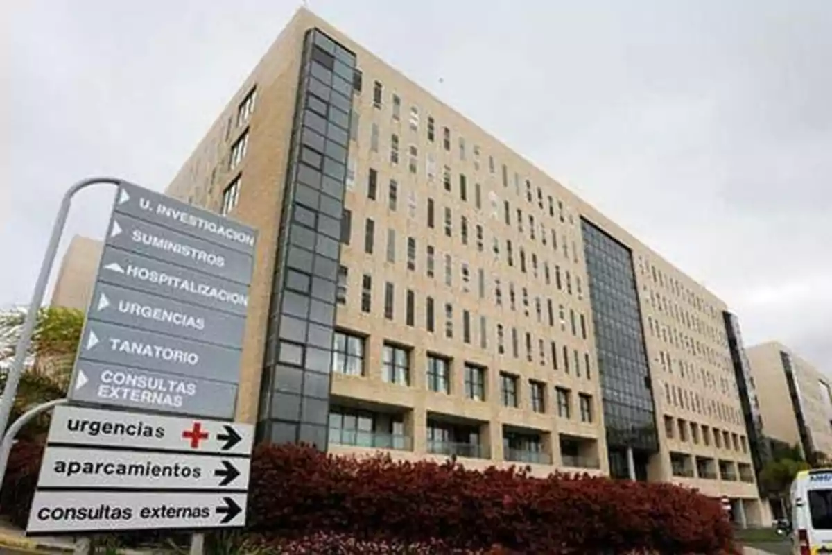 Edificio hospitalario con señalización de diferentes áreas como urgencias, hospitalización y consultas externas.