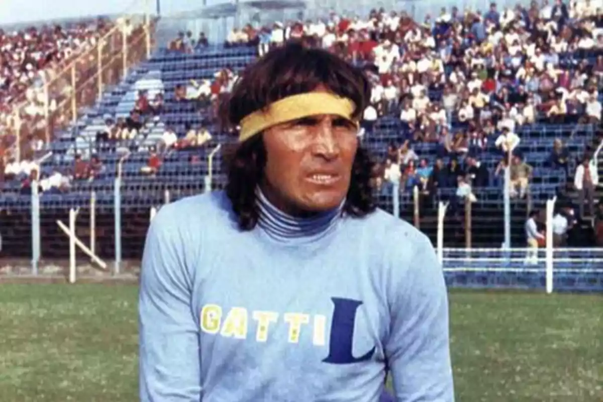 Un futbolista con cinta en la cabeza y camiseta con el nombre "Gatti" en un estadio lleno de espectadores.