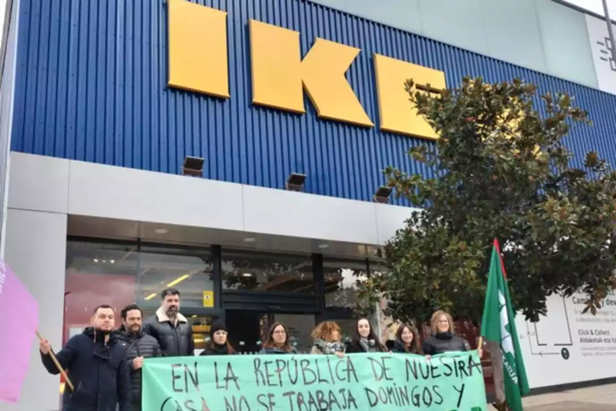 Un grupo de personas sostiene una pancarta verde frente a una tienda de IKEA.