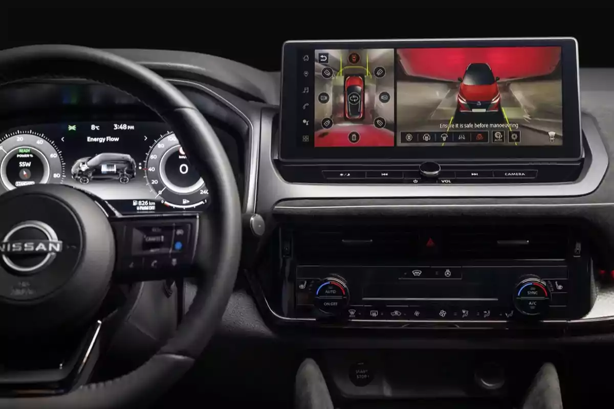 El interior de un automóvil Nissan con un volante y una pantalla de control que muestra la cámara de visión trasera y el flujo de energía del vehículo. El interior de un automóvil Nissan con un volante y una pantalla de control que muestra la cámara de visión trasera y el flujo de energía del vehículo.