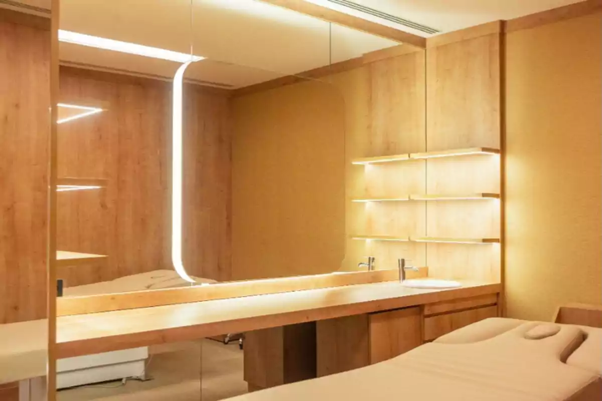 Cuarto de spa moderno con camilla de masaje, espejo grande, estanterías de madera y luz cálida Cuarto de spa moderno con camilla de masaje, espejo grande, estanterías de madera y luz cálida