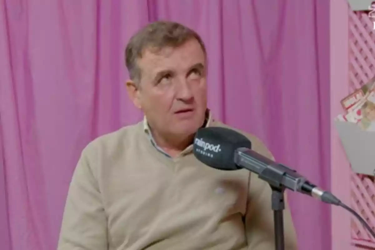 Antonio Montero con suéter beige está hablando frente a un micrófono en un estudio con cortinas rosas. Antonio Montero con suéter beige está hablando frente a un micrófono en un estudio con cortinas rosas.