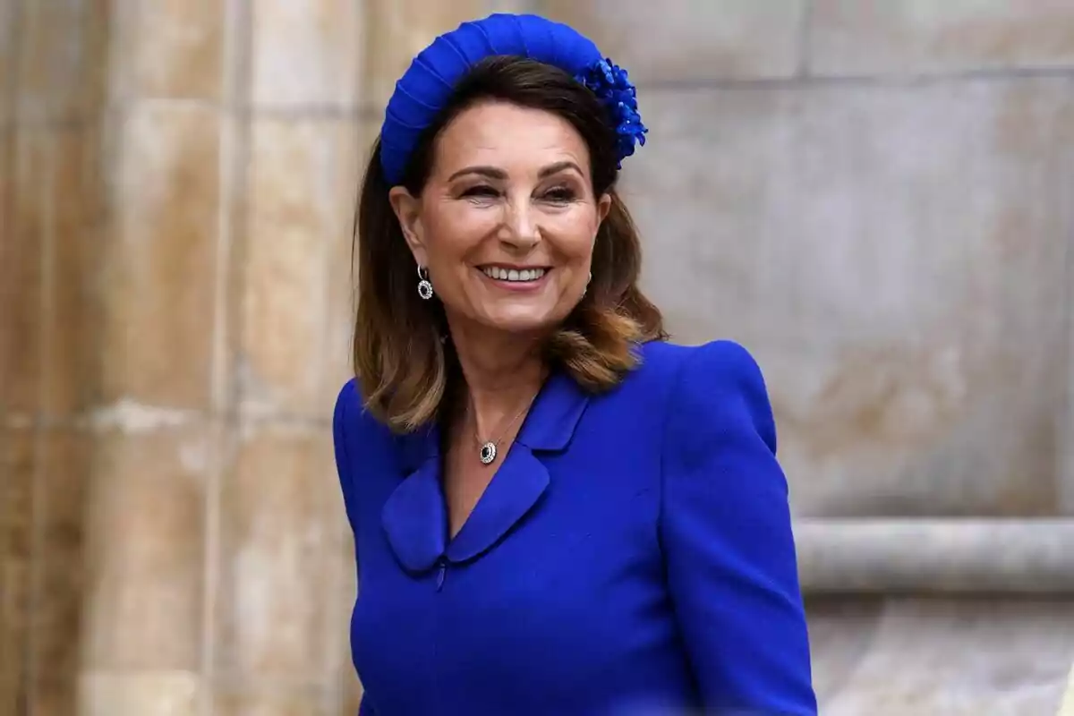 Una mujer sonriente con un vestido azul y un tocado a juego. Una mujer sonriente con un vestido azul y un tocado a juego.