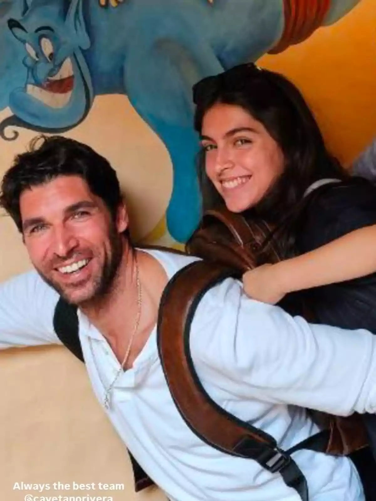 Lucía Rivera y Cayetano Rivera sonrientes posan frente a un mural colorido con un personaje azul. Lucía Rivera y Cayetano Rivera sonrientes posan frente a un mural colorido con un personaje azul.