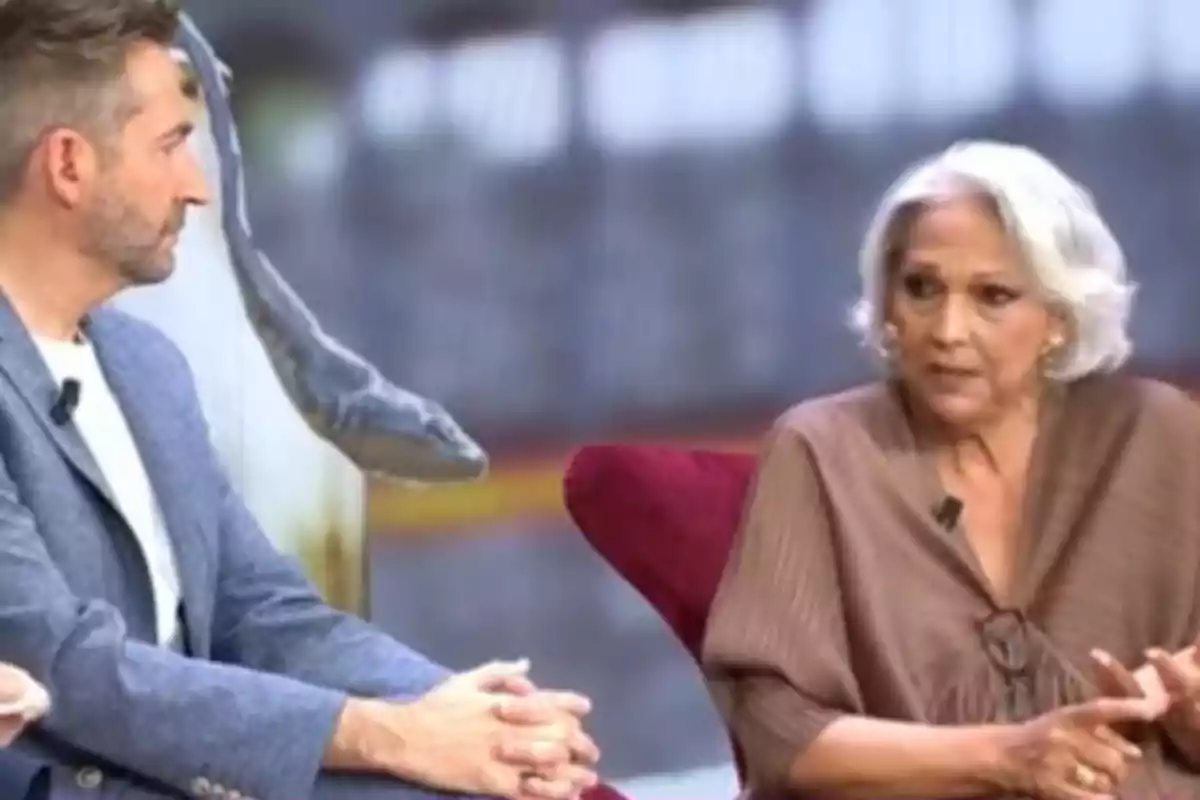 Charo Vega y Frank Blanco sentados en un set de televisión, una de ellas con cabello canoso y la otra con barba, ambas con micrófonos de solapa. Charo Vega y Frank Blanco sentados en un set de televisión, una de ellas con cabello canoso y la otra con barba, ambas con micrófonos de solapa.