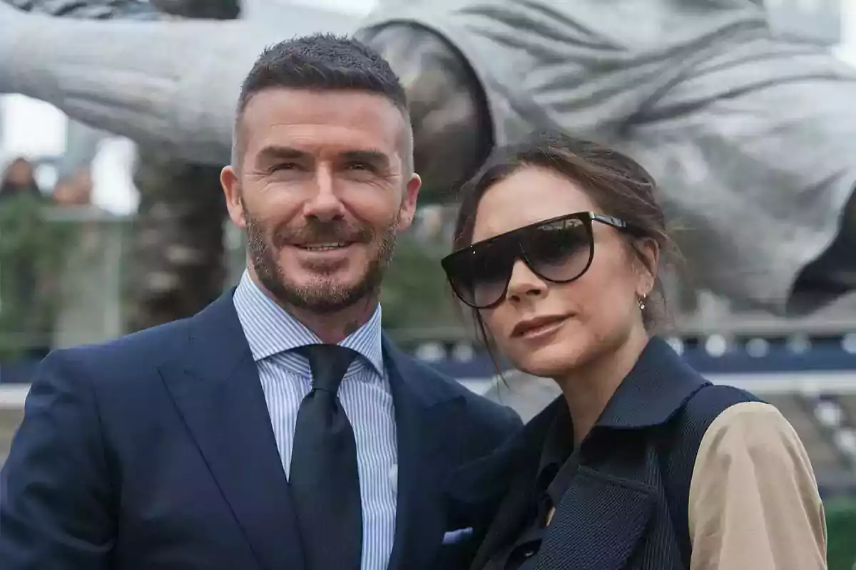 Pareja posando juntos al aire libre ambos vestidos de manera elegante él con traje y corbata y ella con gafas de sol grandes Pareja posando juntos al aire libre ambos vestidos de manera elegante él con traje y corbata y ella con gafas de sol grandes