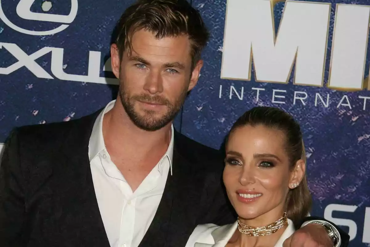 Una pareja, formada por Elsa Pataky y Chris Hemsworth, posando juntos en un evento con fondo azul y letras blancas. Una pareja, formada por Elsa Pataky y Chris Hemsworth, posando juntos en un evento con fondo azul y letras blancas.