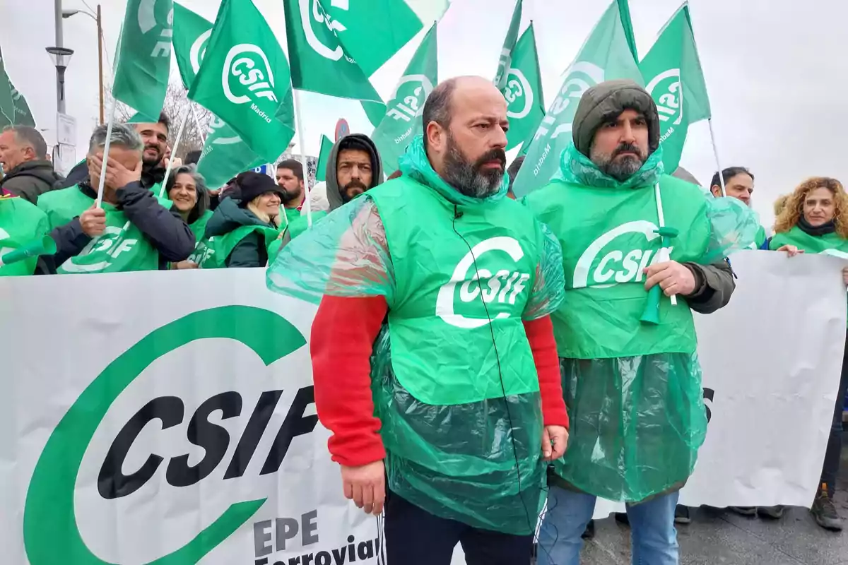 Un grupo de personas vestidas con ponchos verdes y sosteniendo banderas participa en una manifestación organizada por CSIF.