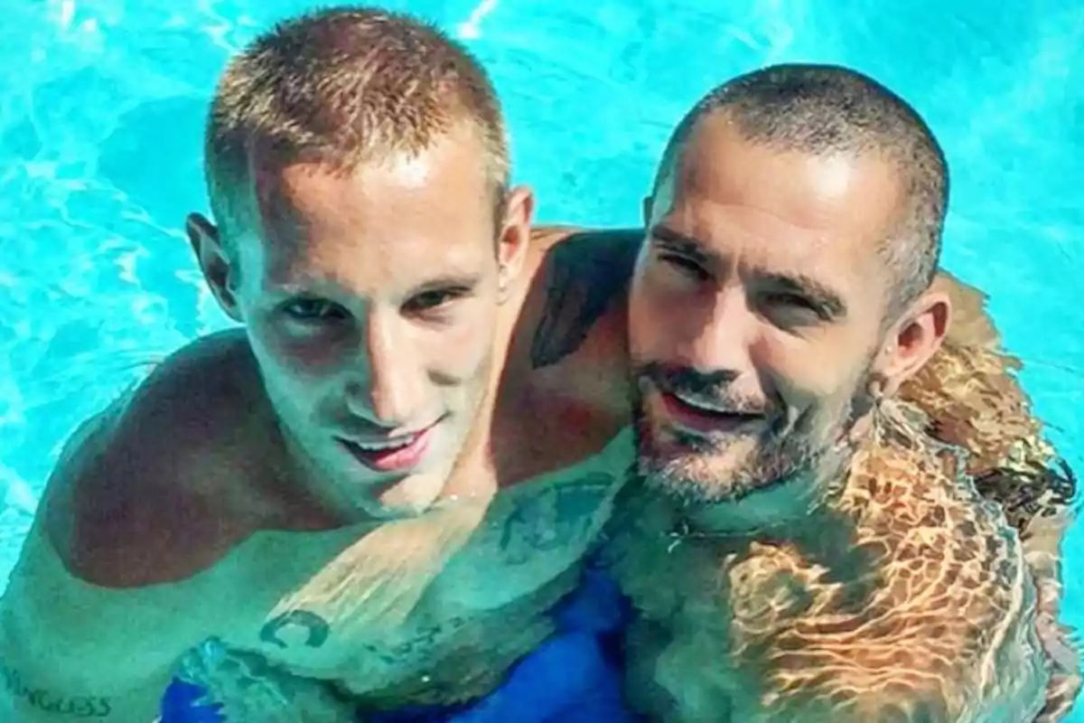 Dos hombres abrazados dentro de una piscina con agua azul