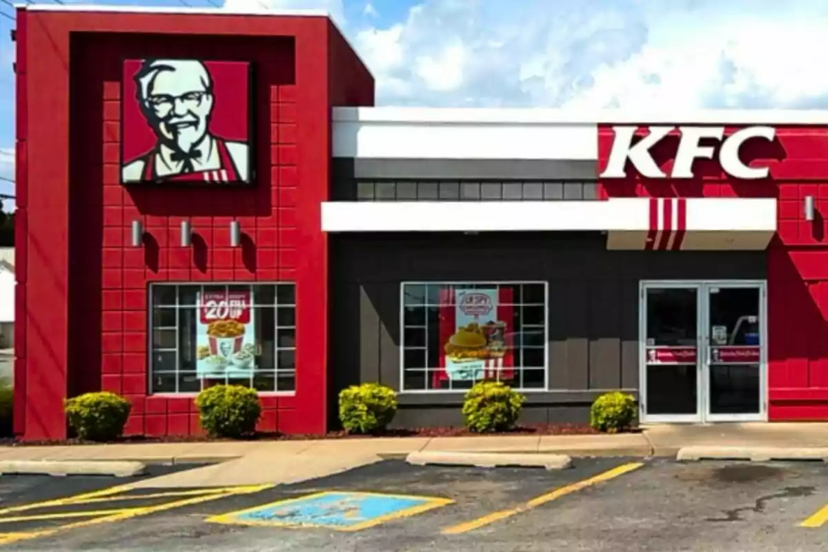 Frente de un restaurante de comida rápida con un diseño exterior en rojo y gris, con un logotipo prominente en la fachada. Frente de un restaurante de comida rápida con un diseño exterior en rojo y gris, con un logotipo prominente en la fachada.