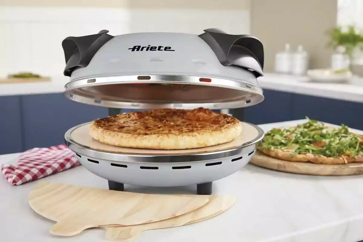 Horno eléctrico para pizza de Lidl con una pizza cocinándose en su interior sobre una encimera de cocina. Horno eléctrico para pizza de Lidl con una pizza cocinándose en su interior sobre una encimera de cocina.