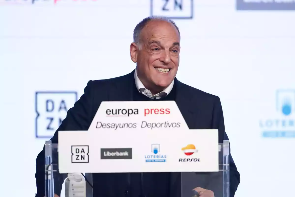 Hombre sonriendo detrás de un podio en un evento de Europa Press Desayunos Deportivos.