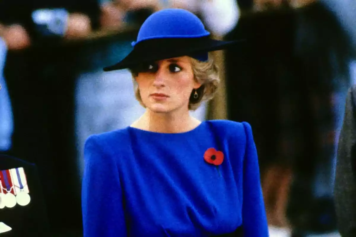 Una persona con un elegante sombrero azul y vestido a juego lleva un broche de amapola roja. Una persona con un elegante sombrero azul y vestido a juego lleva un broche de amapola roja.