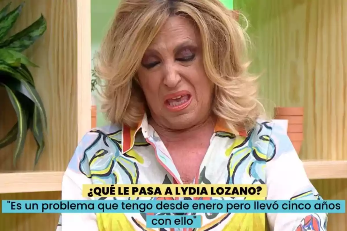 Lydia Lozano rubia con expresión de disgusto o dolor sentada en un set de televisión con plantas de fondo y un texto en pantalla que dice qué le pasa a Lydia Lozano y una cita sobre un problema de salud Lydia Lozano rubia con expresión de disgusto o dolor sentada en un set de televisión con plantas de fondo y un texto en pantalla que dice qué le pasa a Lydia Lozano y una cita sobre un problema de salud