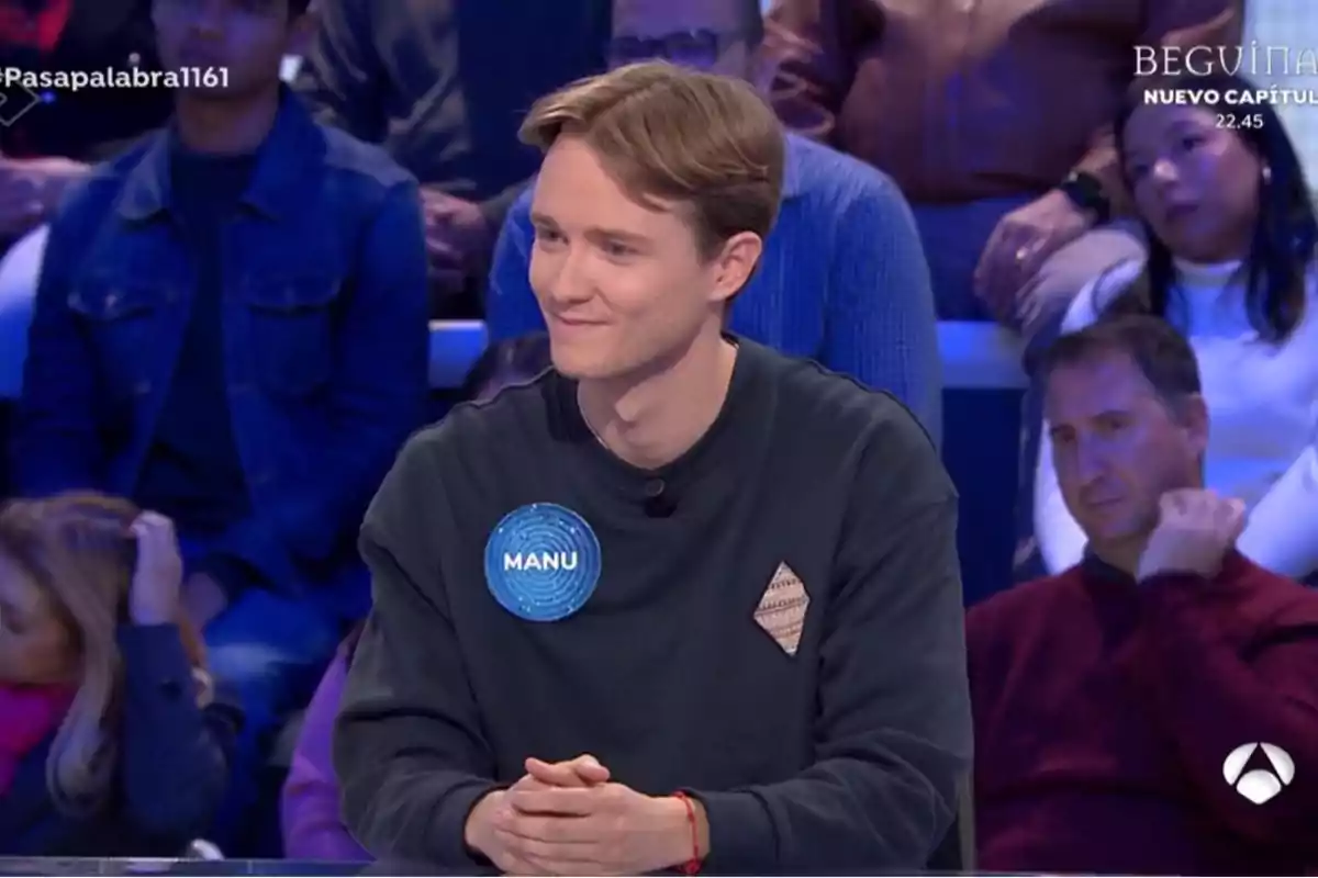 Manu con una sudadera oscura y una etiqueta que dice Manu con una sudadera oscura y una etiqueta que dice