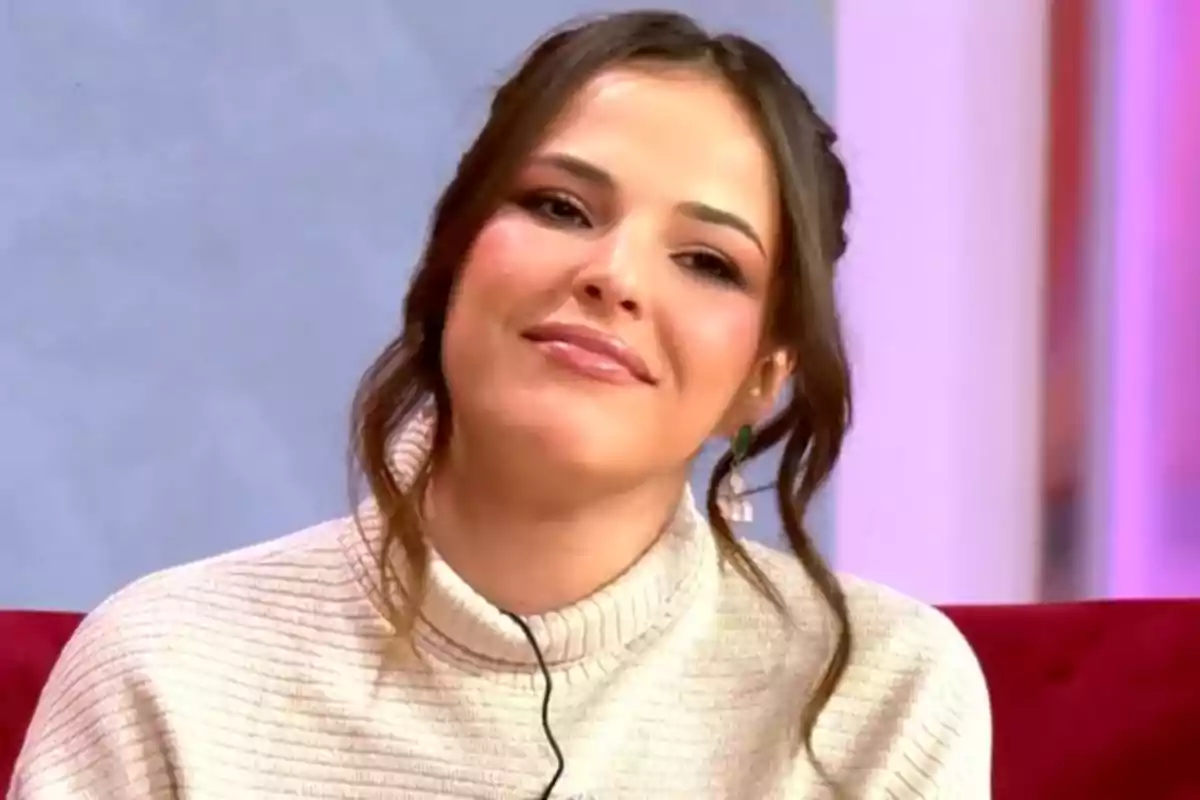 Marta Peñate con cabello castaño y suéter claro sonríe mientras está sentada en un entorno interior. Marta Peñate con cabello castaño y suéter claro sonríe mientras está sentada en un entorno interior.