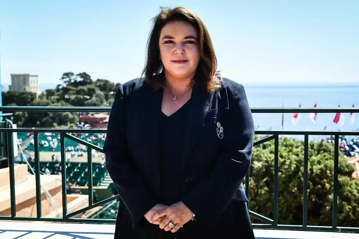 Una persona de pie en un balcón con vista al mar y un paisaje verde al fondo. Una persona de pie en un balcón con vista al mar y un paisaje verde al fondo.