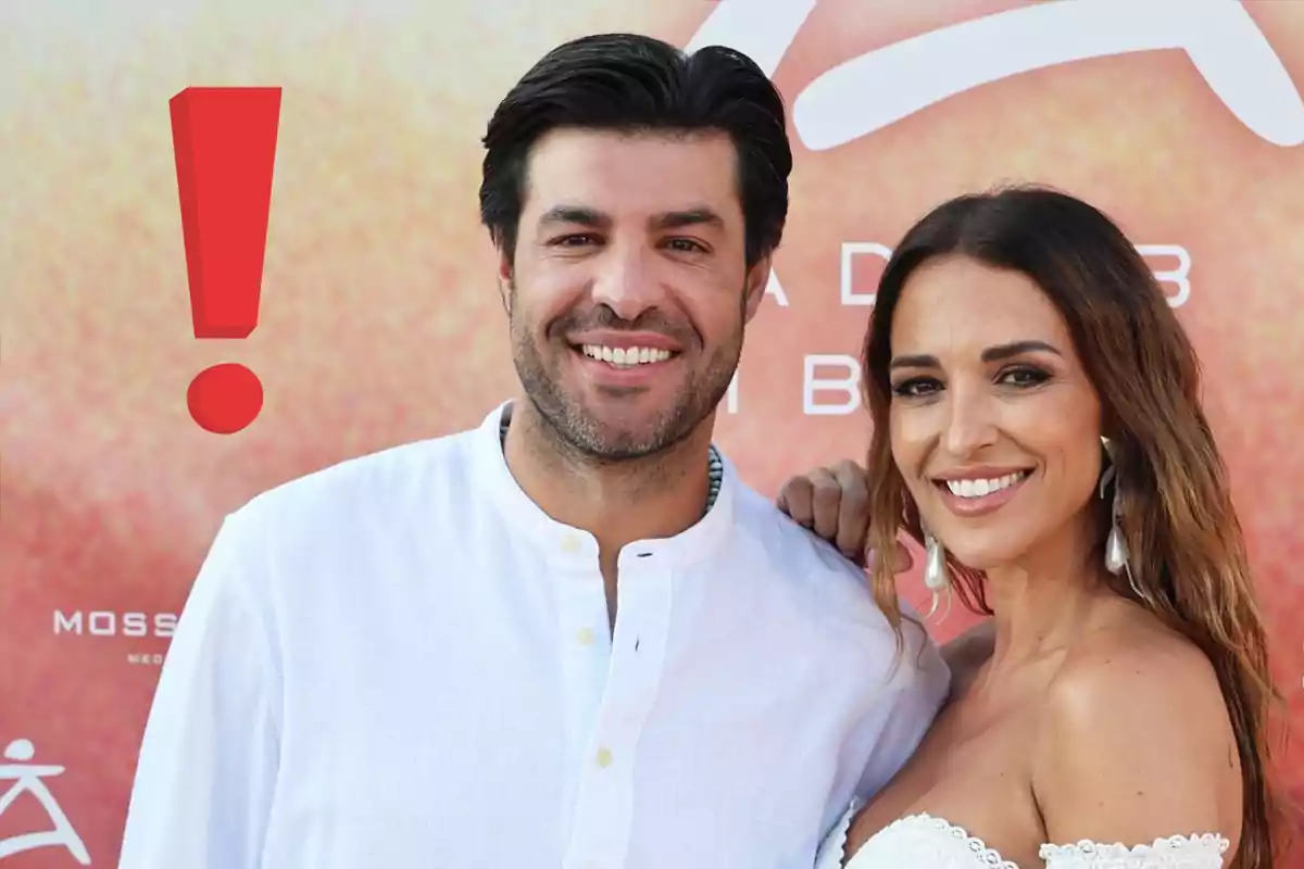 Paula Echevarría y Miguel Torres sonriendo frente a un fondo colorido con un gran signo de exclamación rojo a la izquierda