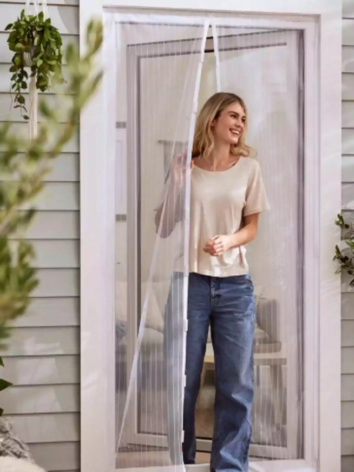 Una persona sonriente con camiseta clara y jeans está saliendo por una puerta con una cortina de malla blanca de Lidl en un entorno exterior. Una persona sonriente con camiseta clara y jeans está saliendo por una puerta con una cortina de malla blanca de Lidl en un entorno exterior.