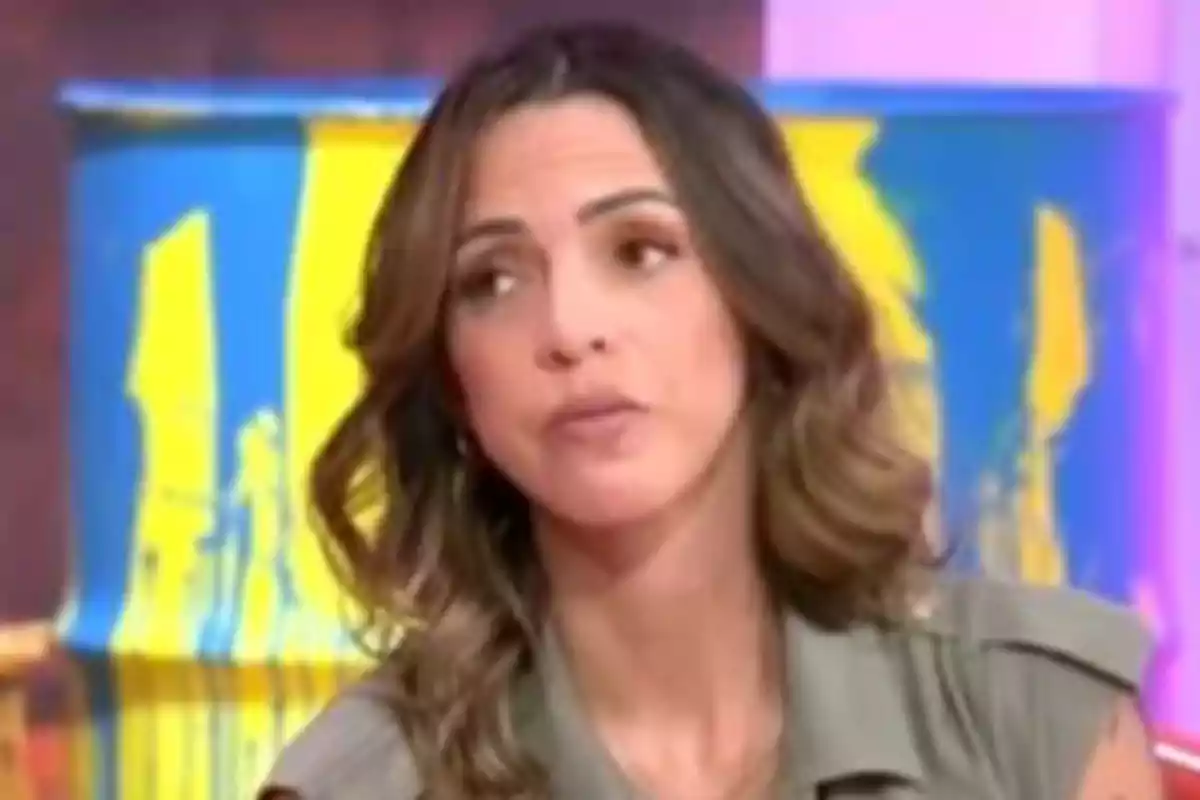 Paola Olmedo con cabello castaño y expresión pensativa está frente a un fondo colorido con un barril pintado de azul y amarillo. Paola Olmedo con cabello castaño y expresión pensativa está frente a un fondo colorido con un barril pintado de azul y amarillo.
