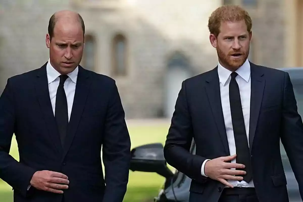 Dos hombres vestidos con trajes oscuros y corbatas negras caminando al aire libre. Dos hombres vestidos con trajes oscuros y corbatas negras caminando al aire libre.
