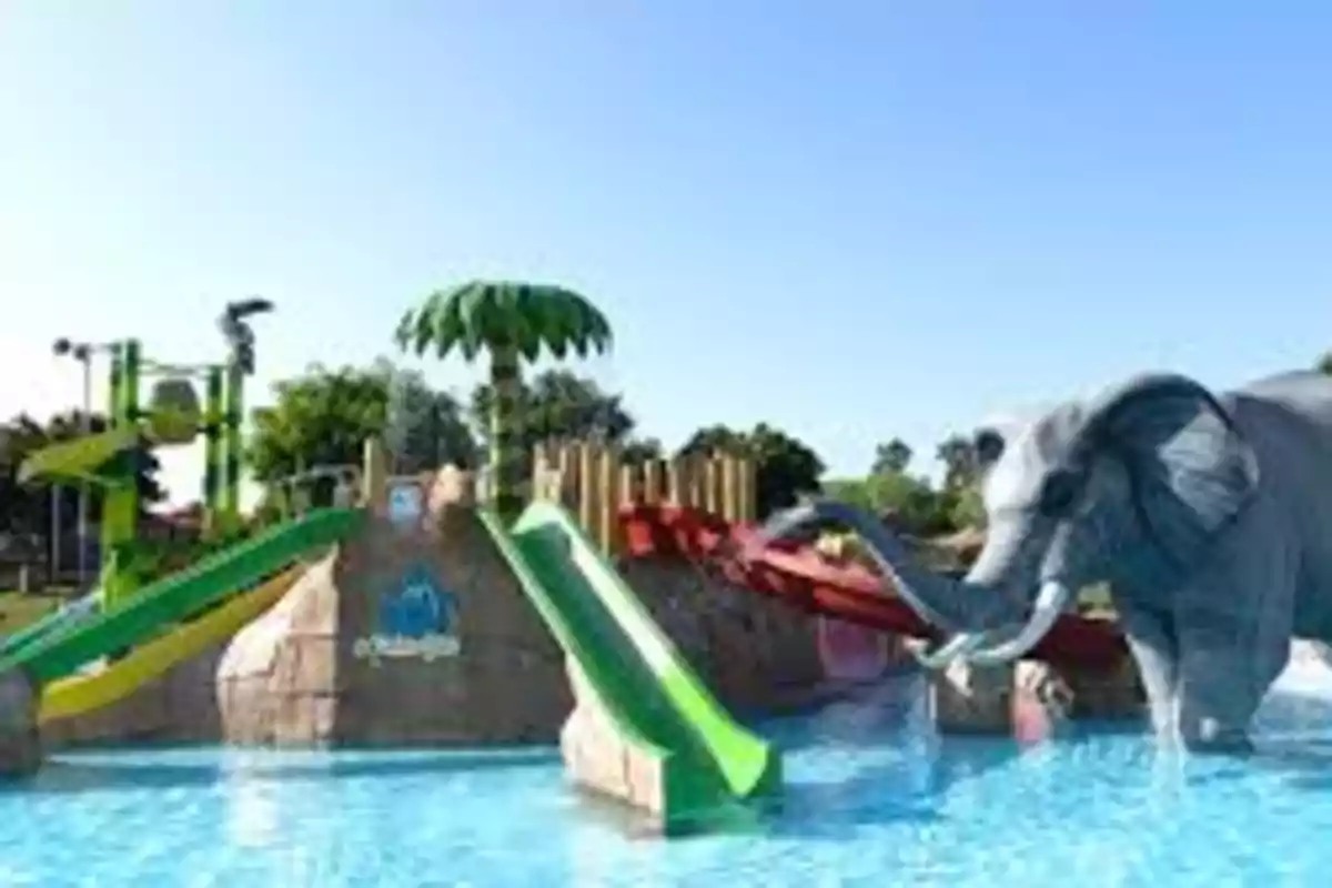 Parque acuático con toboganes de colores y una figura de elefante junto a una piscina.