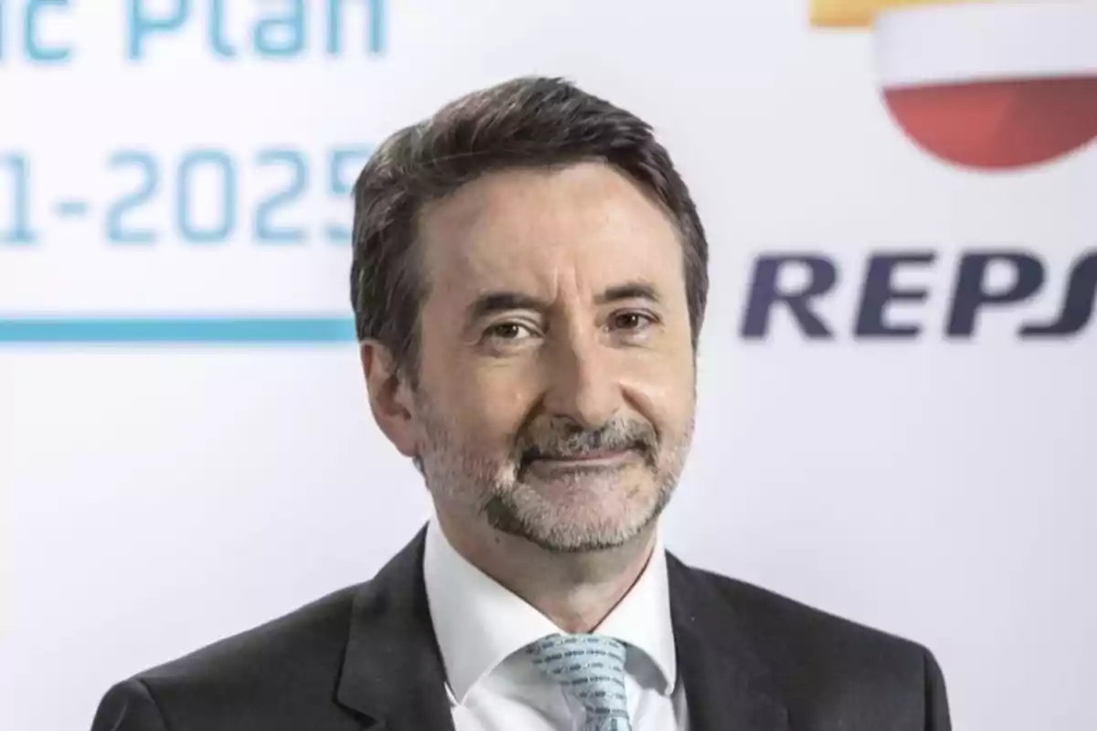 Hombre de traje y corbata sonriendo frente a un fondo con el logo de Repsol.