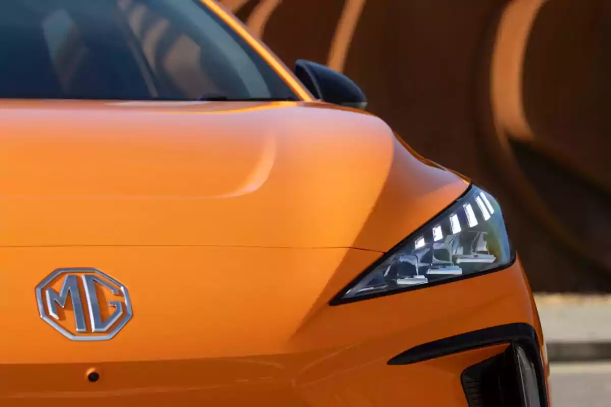 Parte frontal de un automóvil MG 4 EV naranja con el logotipo de MG y faros modernos.