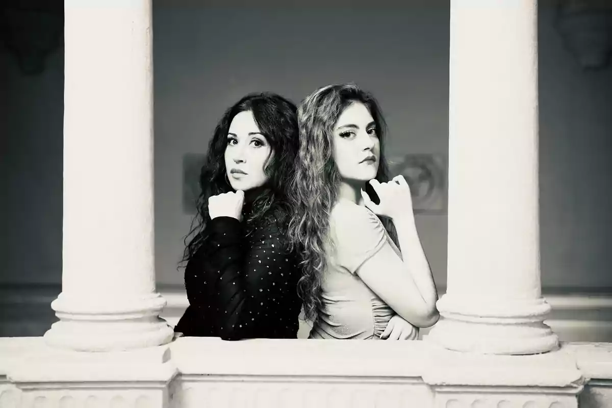 Dos personas posando de espaldas entre columnas en una fotografía en blanco y negro. Dos personas posando de espaldas entre columnas en una fotografía en blanco y negro.