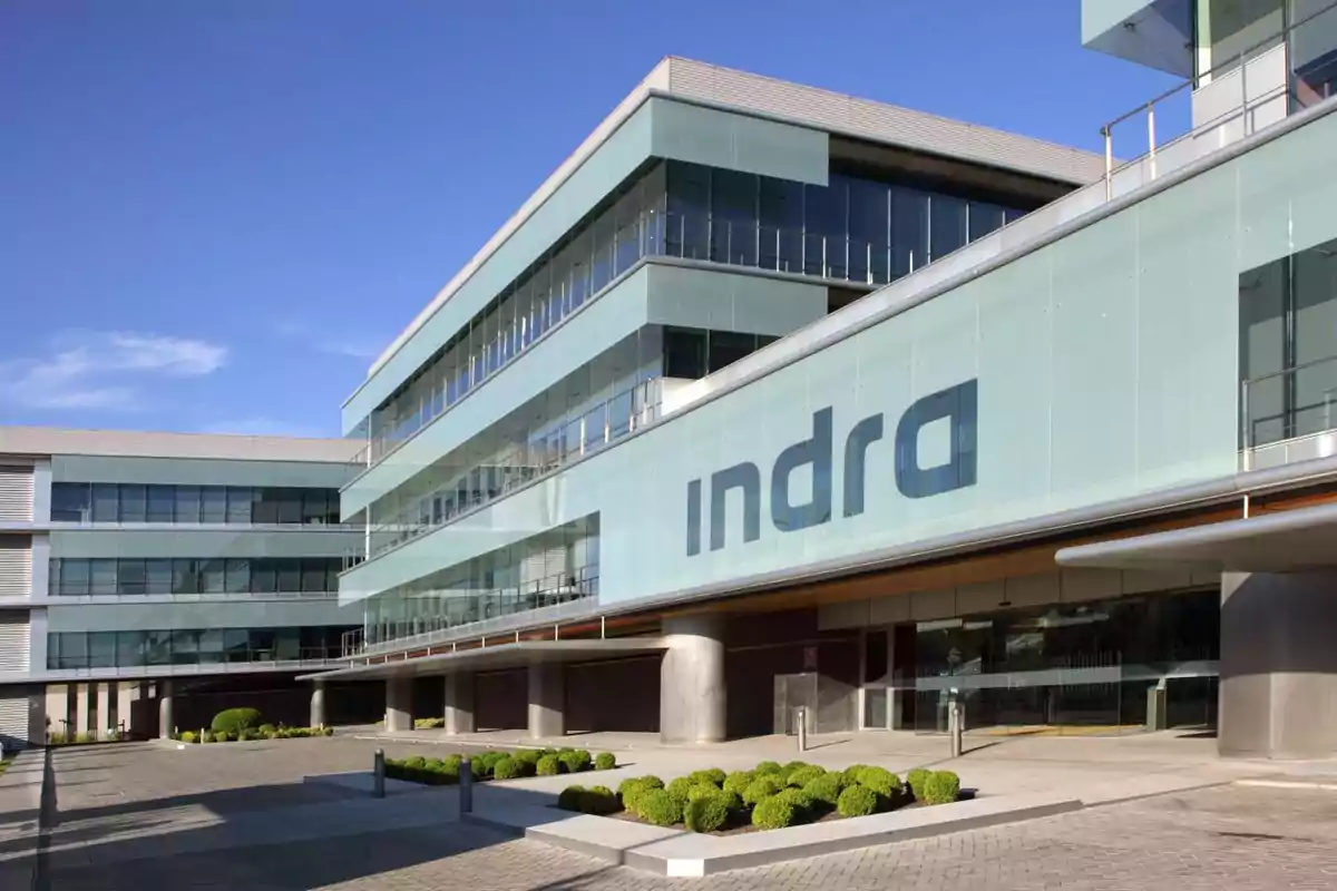 Edificio moderno de oficinas con el logotipo de Indra en la fachada.