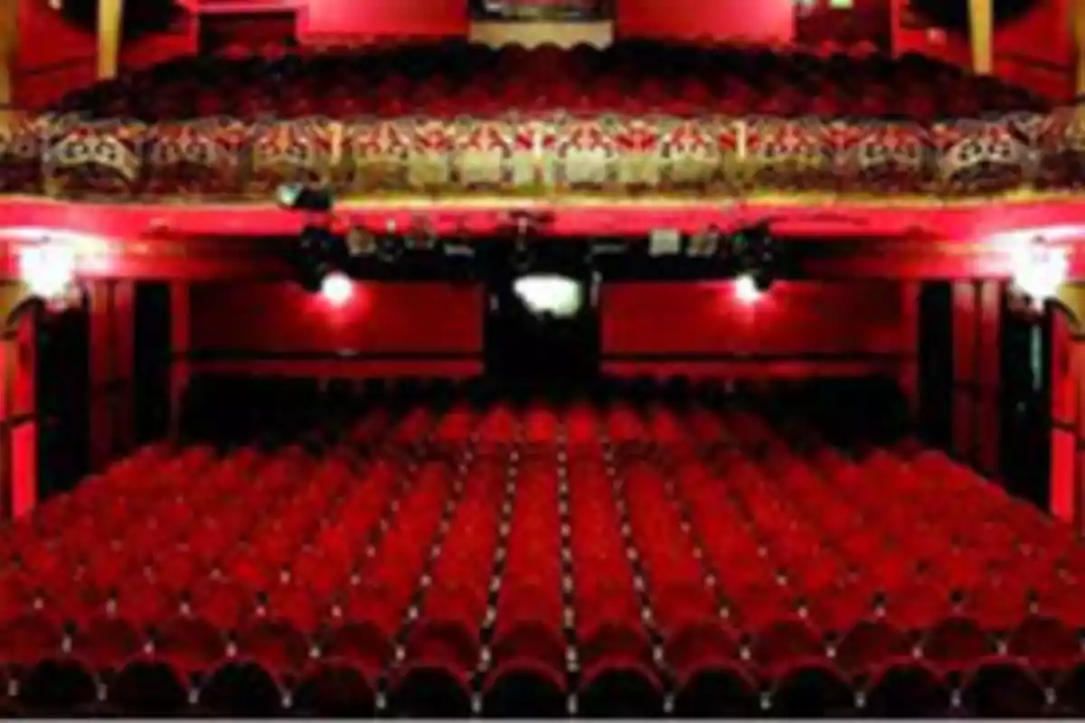 Teatro con asientos rojos y balcón decorado.