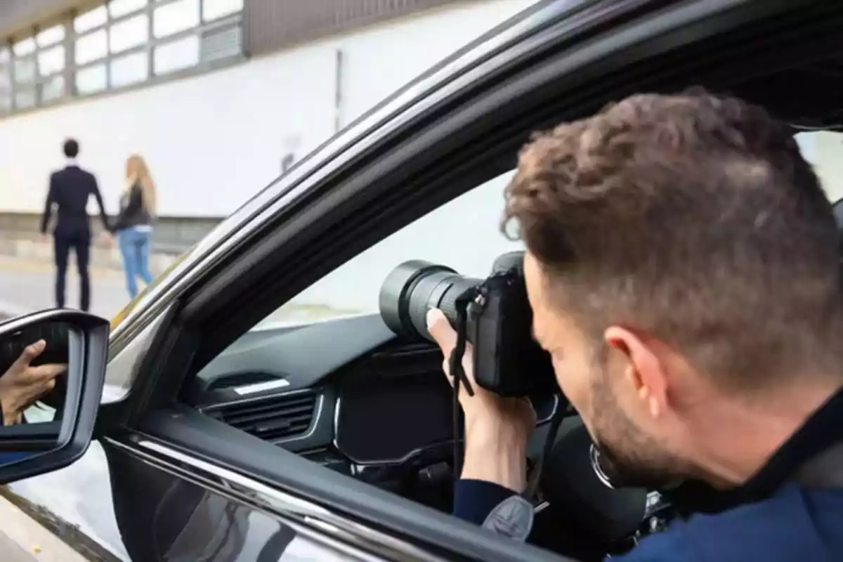 Persona tomando fotos desde un auto mientras observa a una pareja caminando.