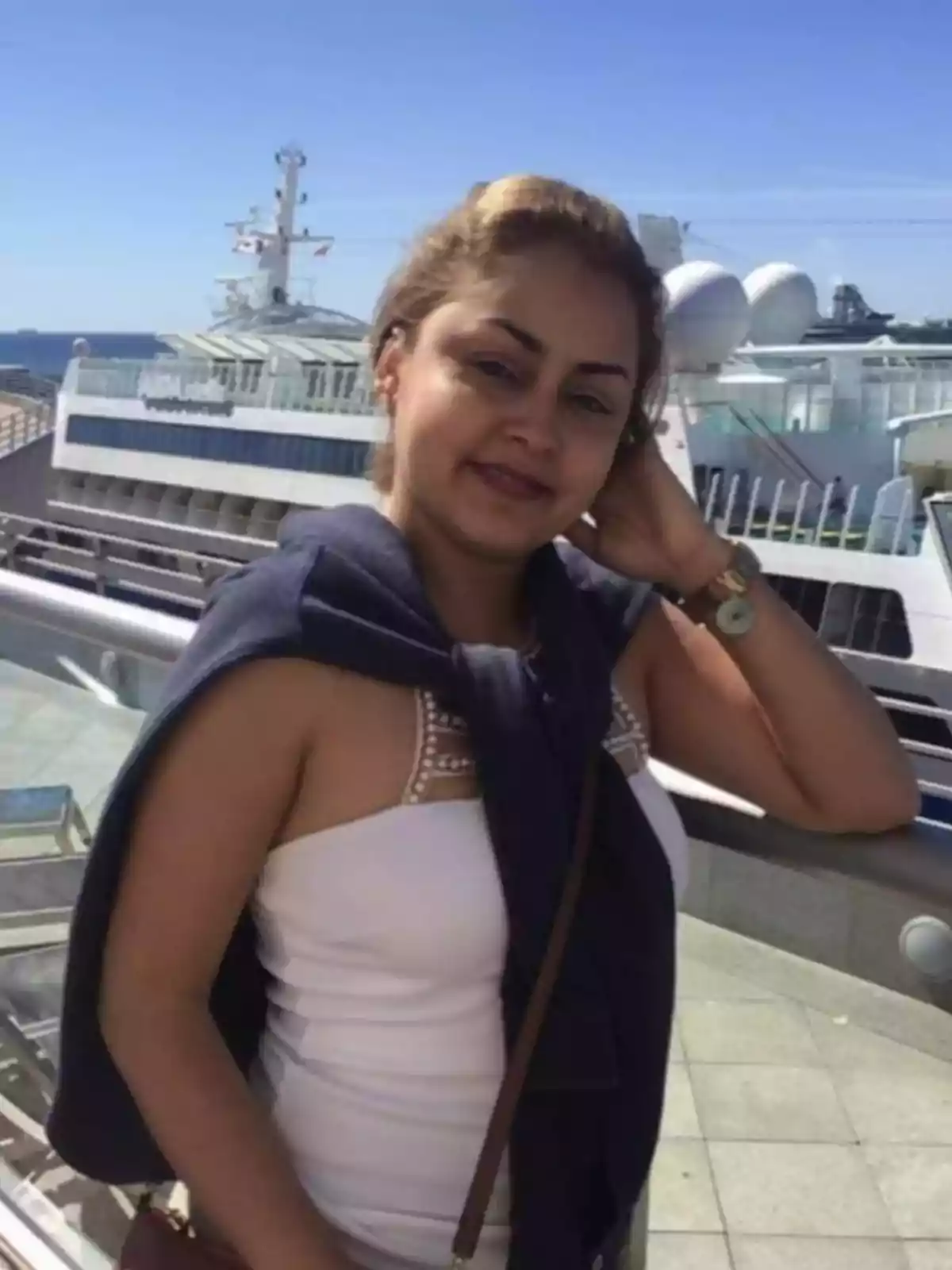 Una mujer posando frente a un crucero en un día soleado.