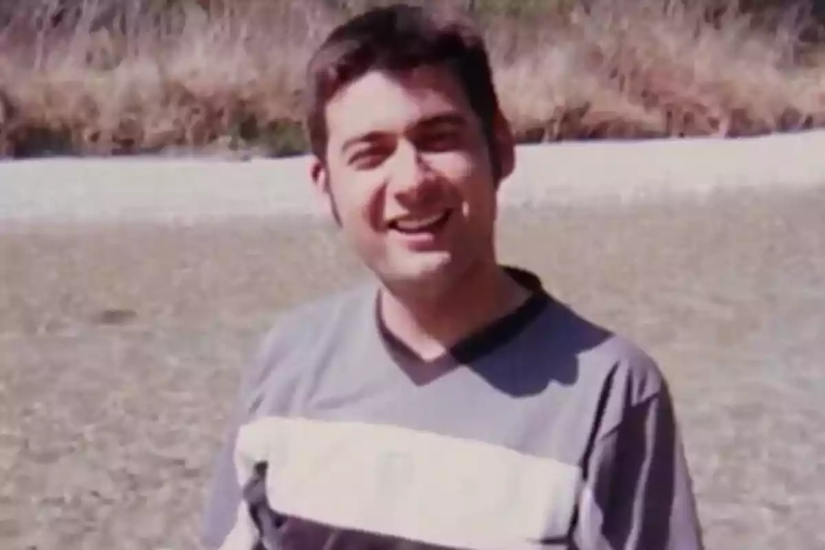 Un hombre sonriente con una camiseta de rayas en un entorno al aire libre.