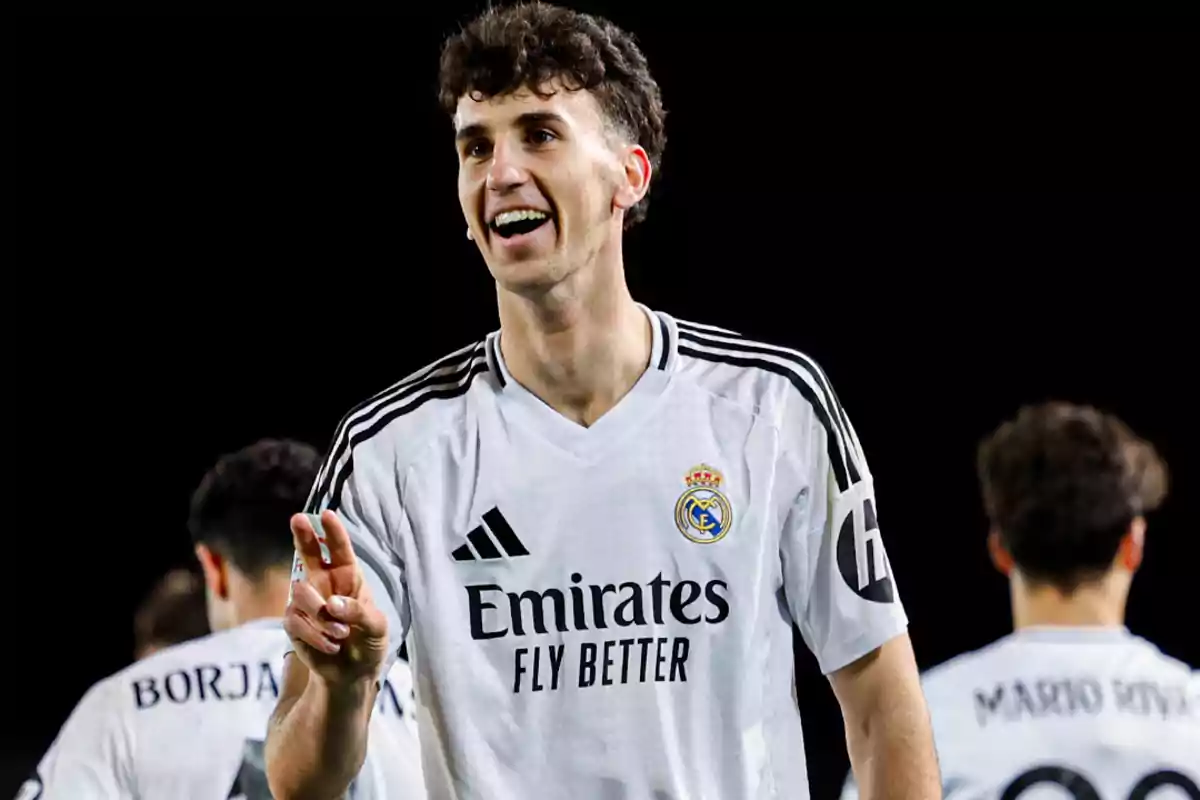 Jugador del Real Madrid sonriente celebrando en el campo de fútbol con la camiseta blanca del equipo Jugador del Real Madrid sonriente celebrando en el campo de fútbol con la camiseta blanca del equipo