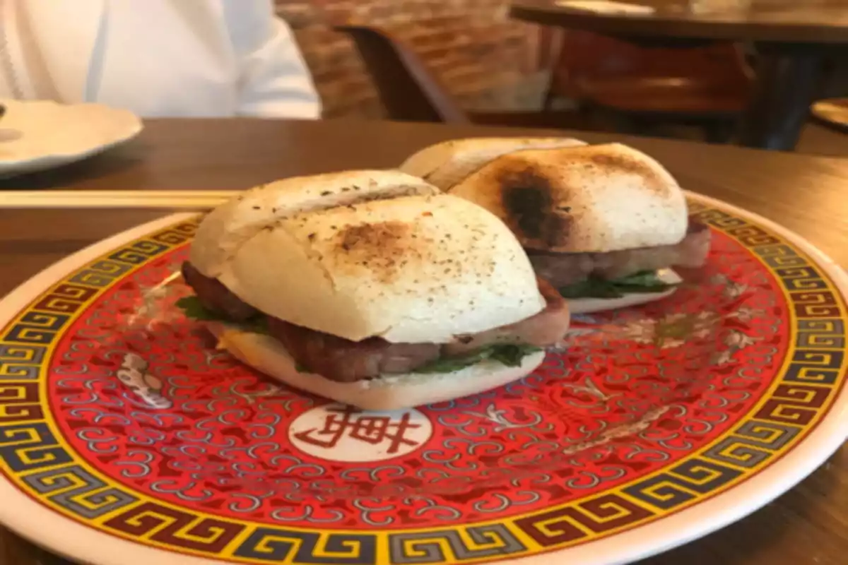 Dos sándwiches en un plato decorativo con diseño oriental.