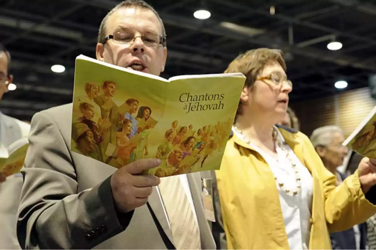 Personas cantando con libros de himnos en una reunión religiosa.