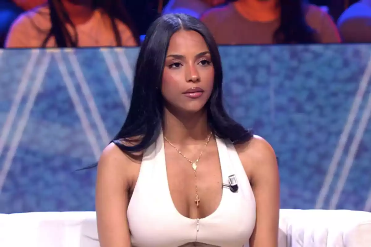 Jeimy Báez sentada en un set de televisión con fondo azul y público desenfocado Jeimy Báez sentada en un set de televisión con fondo azul y público desenfocado