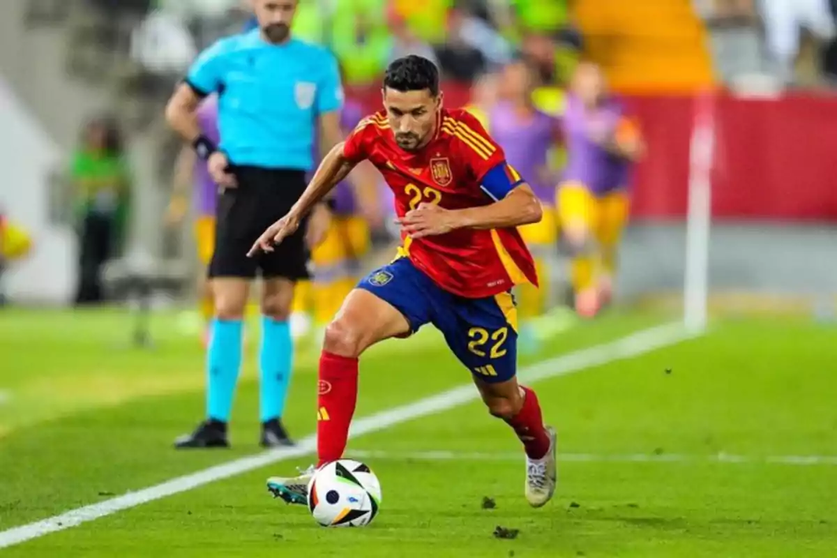 Jugador de fútbol con uniforme rojo y azul controlando el balón en el campo durante un partido.