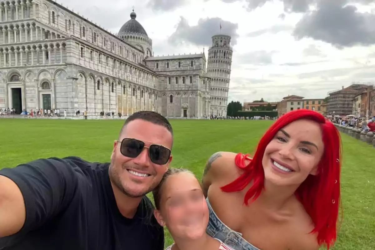 Una familia sonriente posando frente a la Torre de Pisa en Italia.