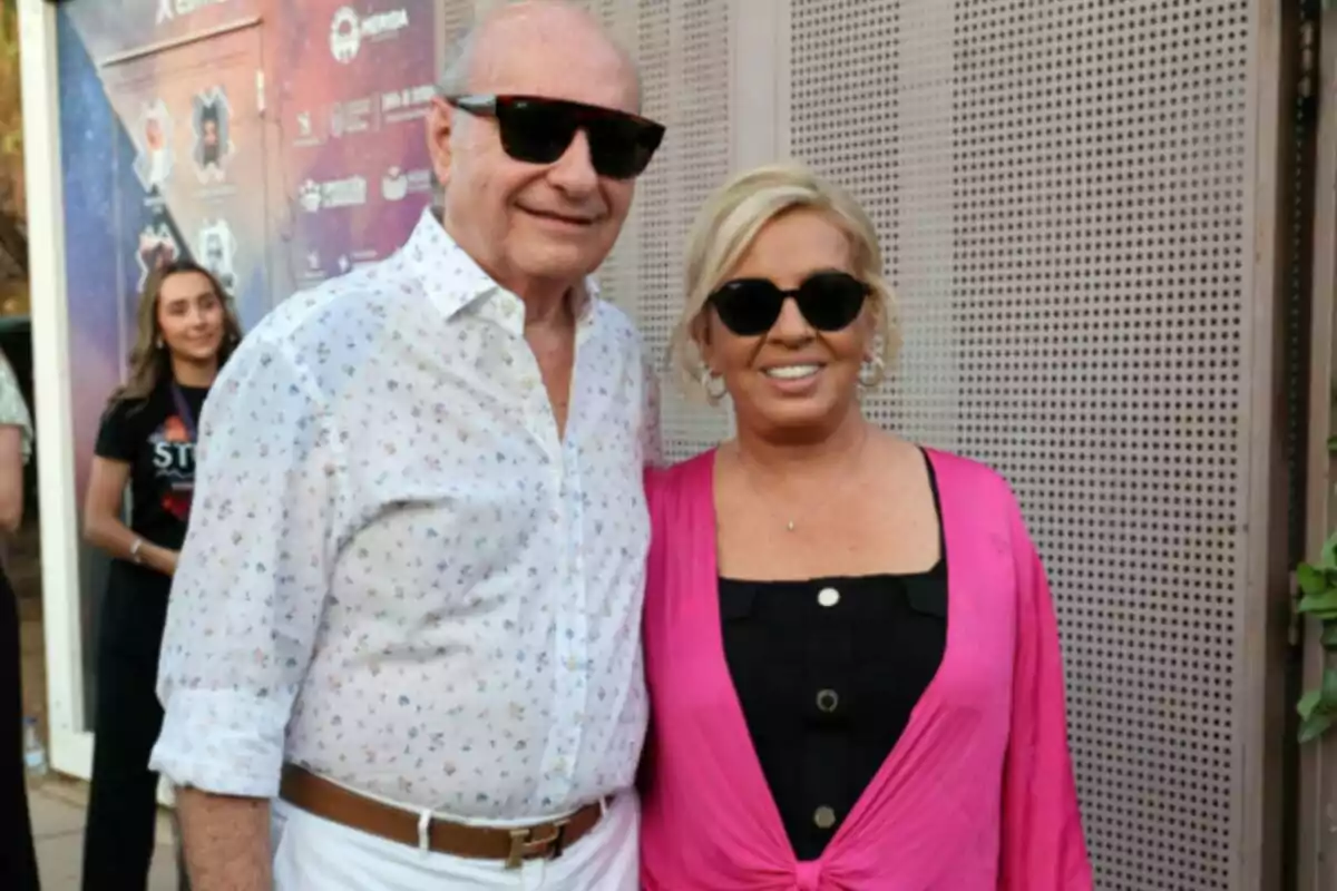 José Carlos Bernal y Carmen Borrego sonriendo y usando gafas de sol en un evento al aire libre, ella lleva un conjunto rosa y negro y él una camisa blanca con estampado y pantalón blanco José Carlos Bernal y Carmen Borrego sonriendo y usando gafas de sol en un evento al aire libre, ella lleva un conjunto rosa y negro y él una camisa blanca con estampado y pantalón blanco