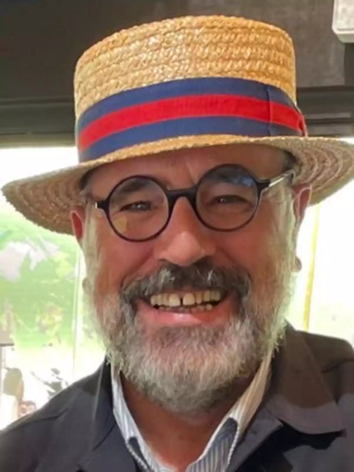 Hombre con sombrero de paja y gafas sonriendo.