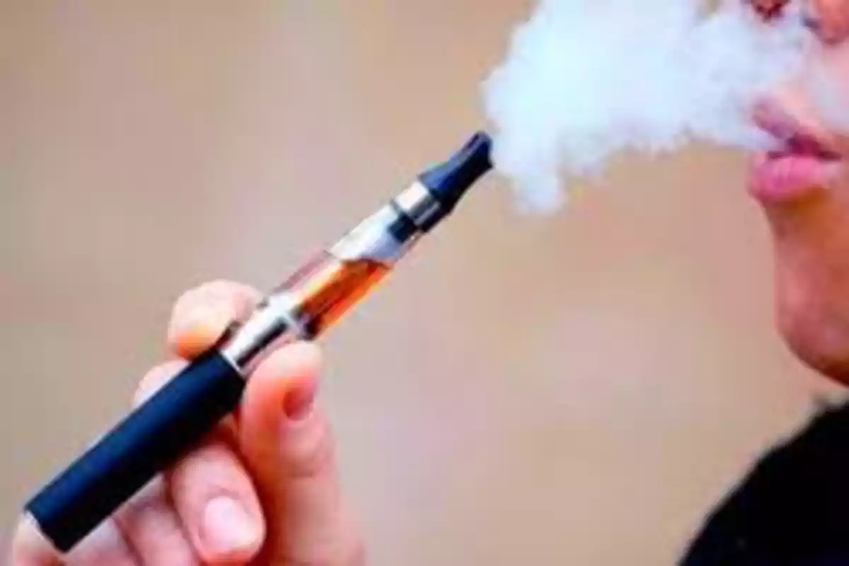 Persona usando un cigarrillo electrónico mientras exhala vapor.